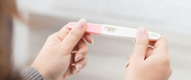 Image of hands holding a home pregnancy test with a positive result.