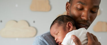 image of man holding snoozing infant to his shoulder