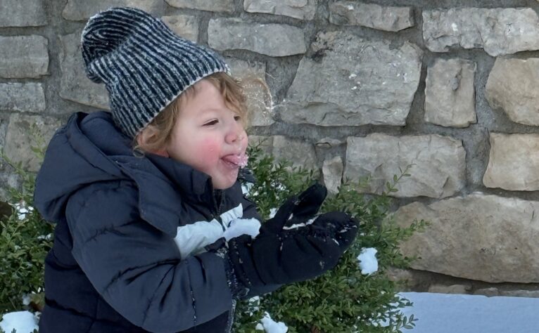 Baby catching snowflakes outside