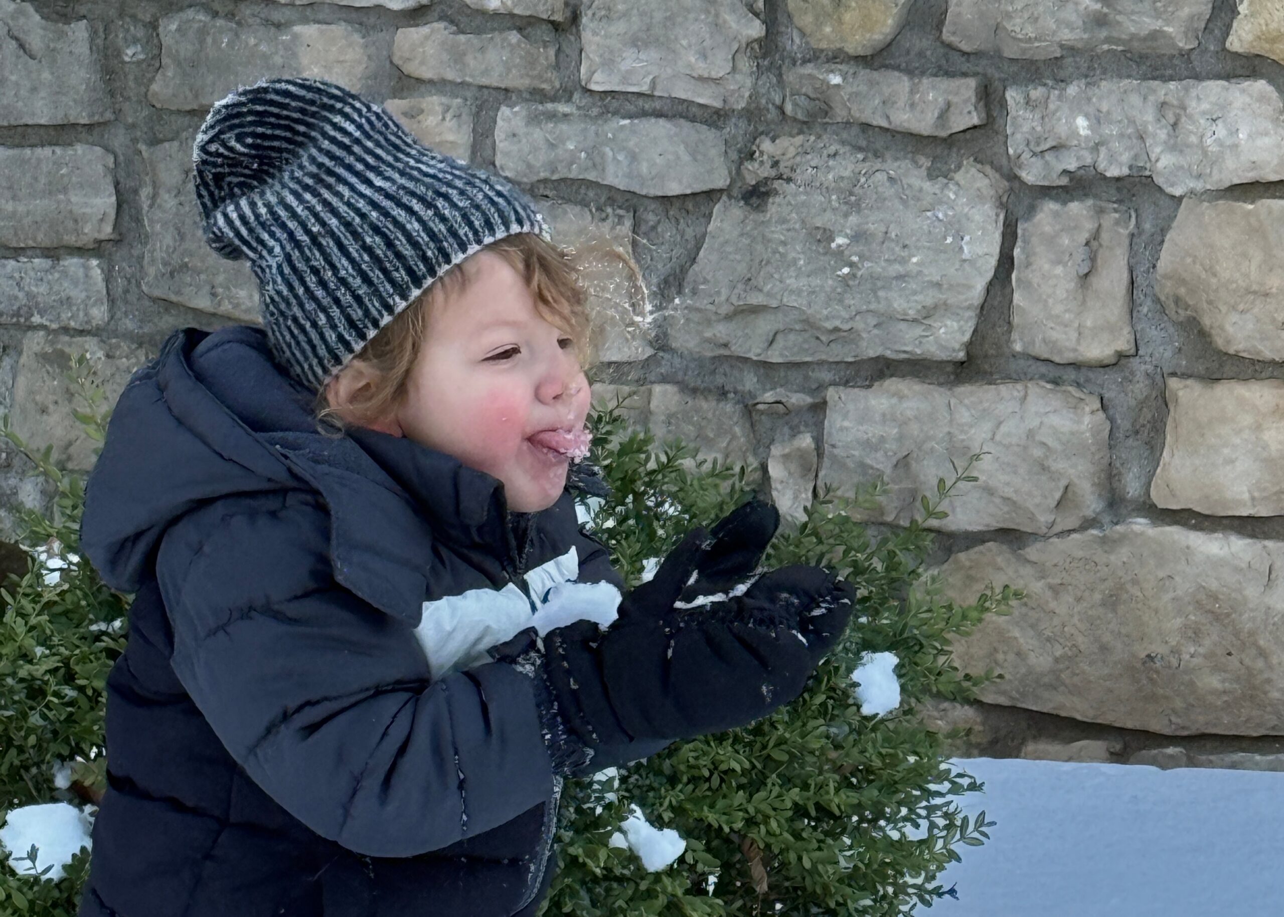 Baby catching snowflakes outside