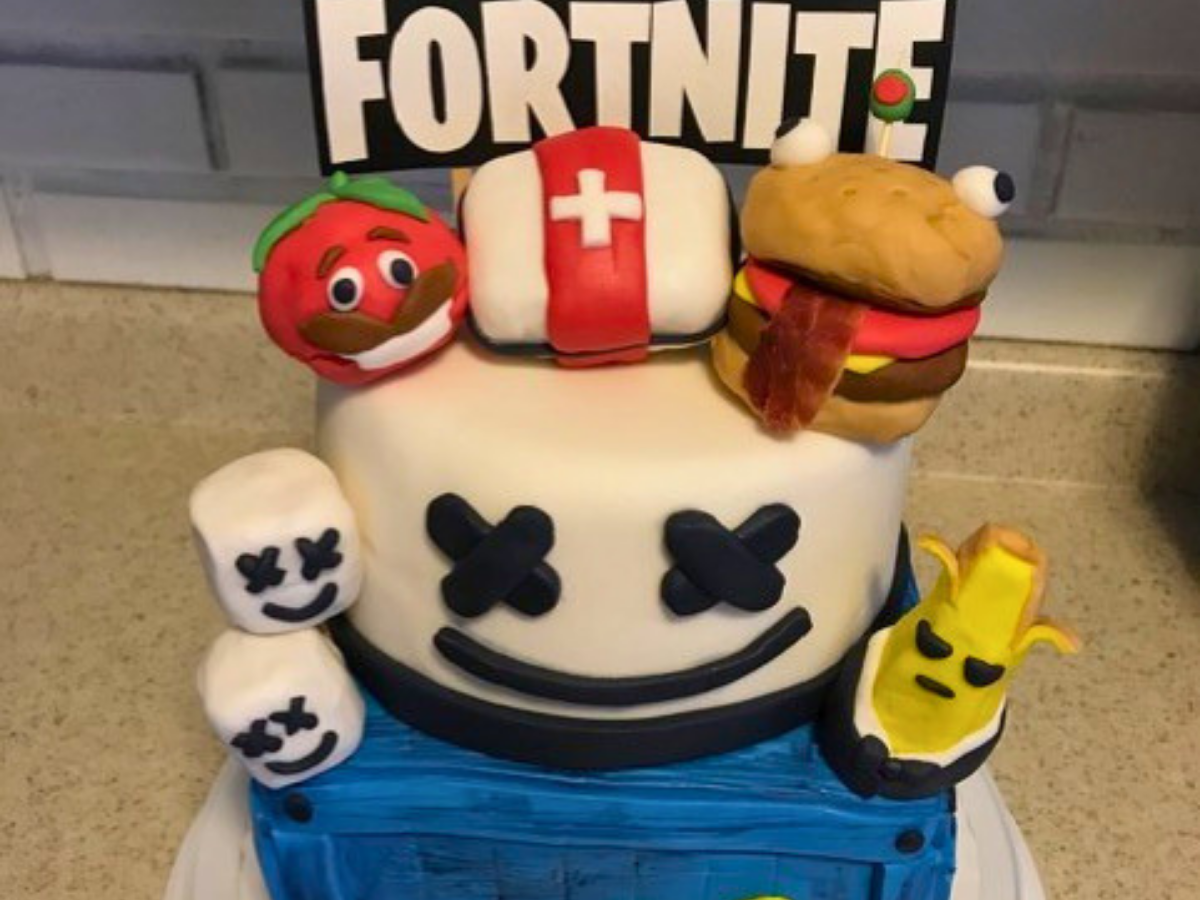 Fortnite-themed birthday cake with characters like Tomato Head, Medkit, burger, and a smiling skull on the front.