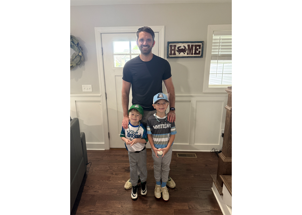 Father standing behind two smiling boys in a home entryway or living area