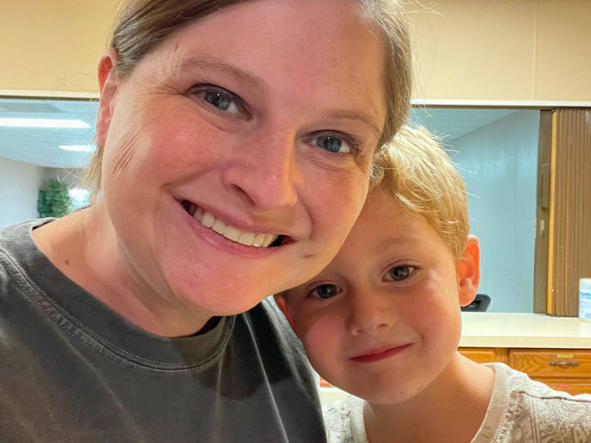 Woman and young boy smiling for a selfie indoors.