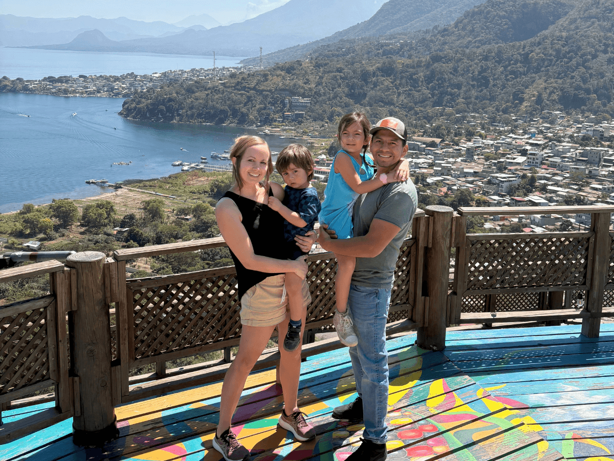 Family of four posing together on a colorful overlook with a coastal town and mountains in the background