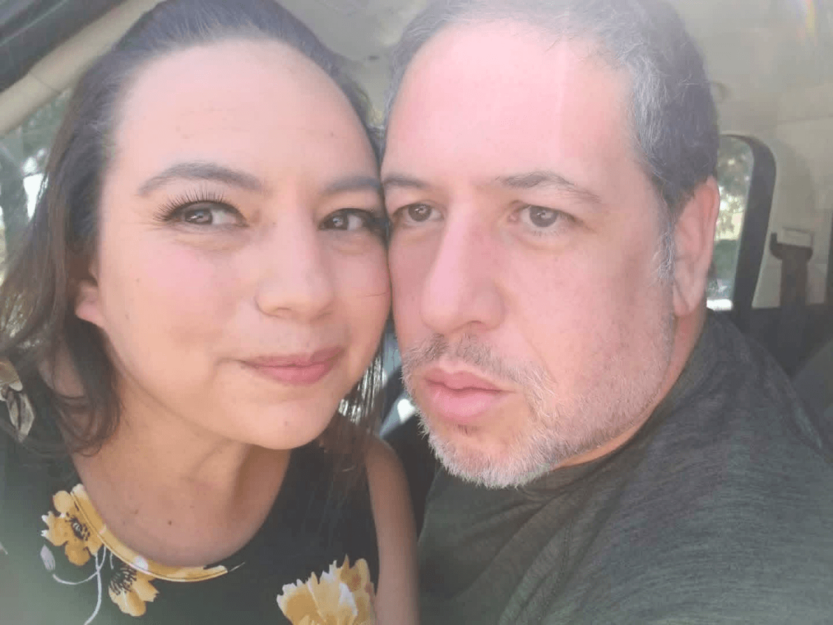 Close-up of a smiling woman and a man in a car, heads touching for a selfie.